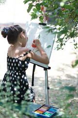 A girl is painting a picture on an easel.