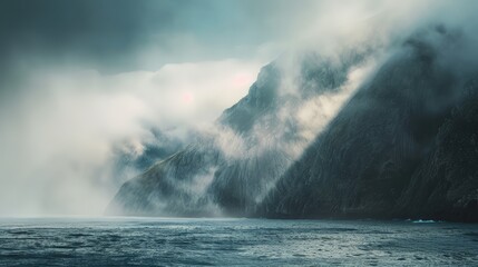 A foggy, misty day with a rocky coastline and a mountain range in the background