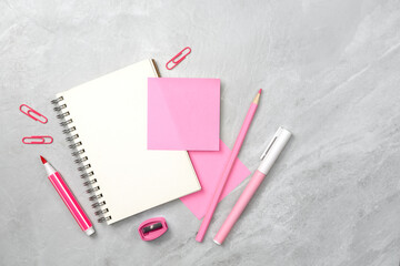 Notebook and pink sticky note and stationery on stone texture background. Work desk space