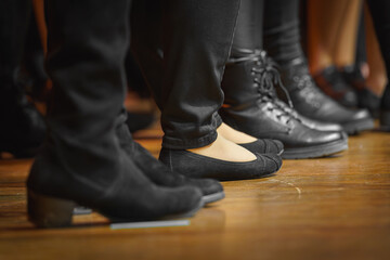 Die Beine, Füße und schwarzen Schuhe von aufgereiten Menschen auf einer Bühne.