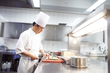 Chef, man and knife in kitchen for food industry, catering service or prepare dish. Hospitality, professional and asian person cutting for cooking meal, fine dining or dinner in restaurant in China
