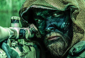 A camouflaged soldier with a piercing gaze, in tactical gear, keeps watch, in the jungle forest...