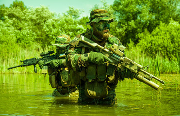 Soldiers move in the heart of a marsh, crossing swampy waters, tropical jungle heat, extreme...