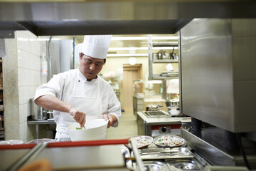 Chef, cooking and Asian man in restaurant with bowl mixing ingredients for meal, dinner or lunch....