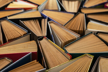 Old and well used hardback books or text books in a book shop or library. Many Books Piles.