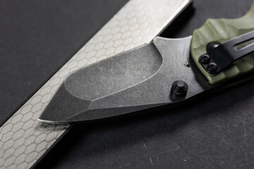 Man sharpens a knife using a whetstone on a dark table