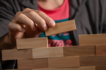 Man holding blocks wood game Build wall. close up
