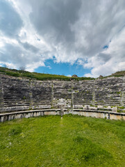 Low-angle view of the historic amphitheater in Aphrodisias under a dramatic cloudy sky, emphasizing the structure's grandeur and ancient design.