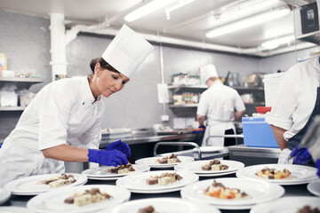 Cooking, chef and woman in restaurant kitchen with plate for fine dining, food service or...