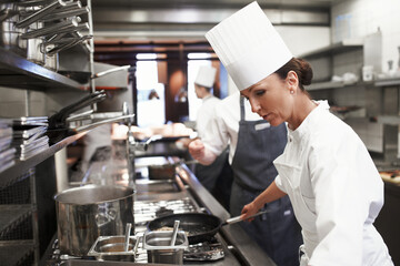 Cooking, chef and woman in kitchen at restaurant for fine dining, service or hospitality industry....