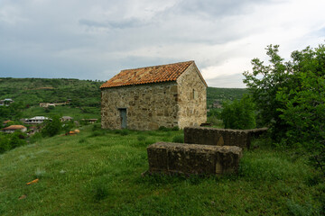 Gravestones in the courtyard of Church of Saskhori village, Georgia. Orange tile roof, Stone walls.