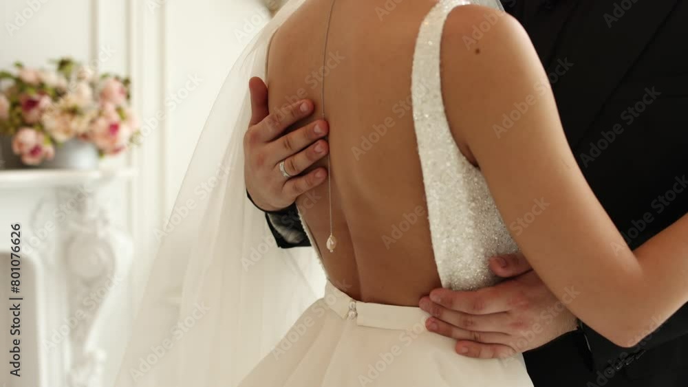 Poster the bride's hand on the groom's jacket at the wedding