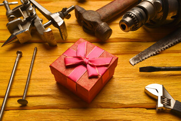 Labor day or father day concept background. Present gift box and work tool on the yelllow workbench...