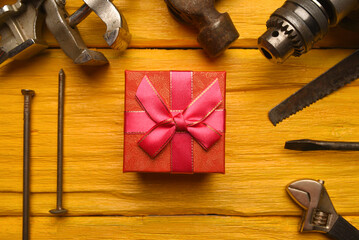 Labor day or father day concept background. Present gift box and work tool on the yelllow workbench...