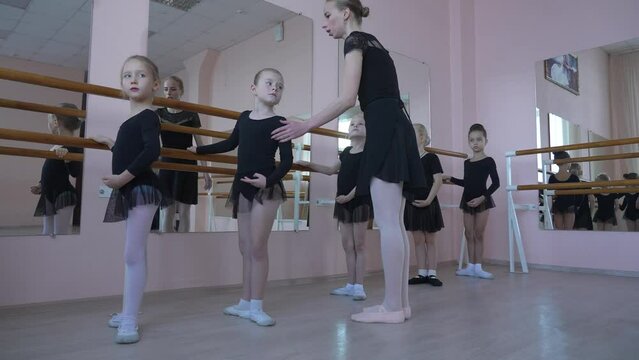 Children's ballet school. Caucasian woman teaching ballet to little girls. 