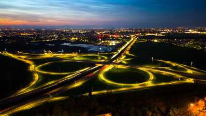 A network of illuminated roads and roundabouts stand out against the night in Milan by Italy