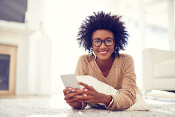 Black woman, portrait and afro with phone on living room floor for social media, blog or reading...