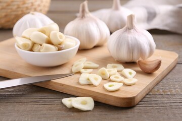 Aromatic cut garlic, cloves and bulbs on wooden table, closeup
