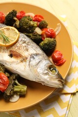 Delicious baked fish and vegetables on table
