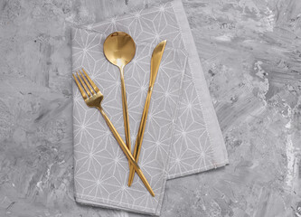 Beautiful cutlery set and kitchen towel on grey table, top view