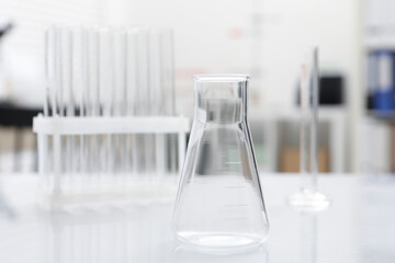 Laboratory analysis. Flask and test tubes on white table indoors, closeup