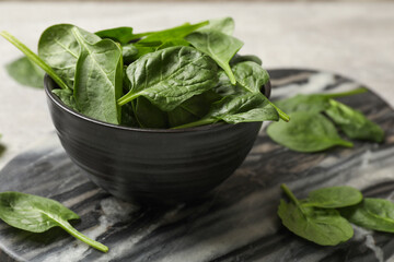 Fresh spinach leaves in bowl on table, closeup