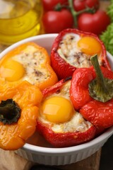 Delicious stuffed peppers with eggs in bowl on table, closeup