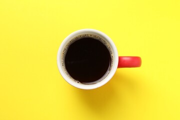 Aromatic coffee in cup on yellow background, top view