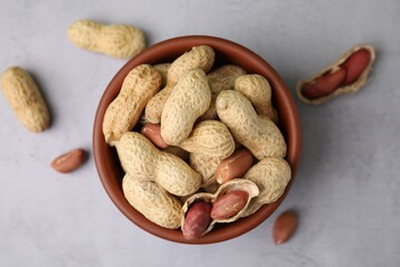 Fresh unpeeled peanuts in bowl on grey table, top view