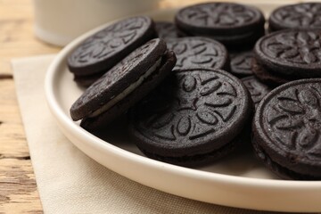 Plate with tasty sandwich cookies on wooden table, closeup