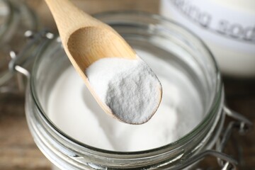 Taking baking soda from jar at table, closeup