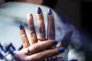 A woman's hands are painted with blue nail polish