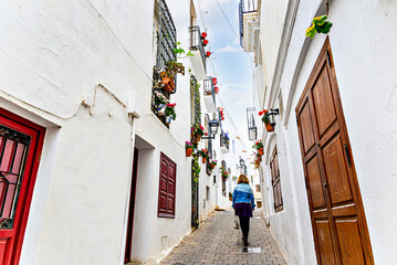 Blonde woman with curly hair walking through the streets of the picturesque town of Mojacar, Almeria, Spain