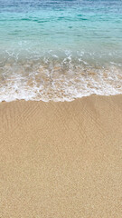 a close up of a wave crashing onto a sandy beach.