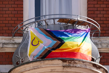 rainbow pride flag progress on balcony house, with black, brown, and blue lines trans flag in...