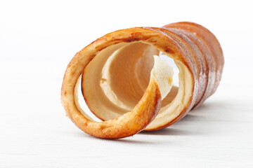 Traditional Hungarian donuts (K&uuml;rt&ouml;skal&aacute;cs), commonly known as chimney cake, on a white wooden background from the front view, with selective focus.