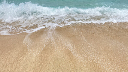 a close up of a wave crashing onto a sandy beach.