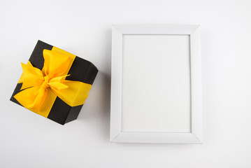 Top view photo of gift box and white wooden frame with empty space.