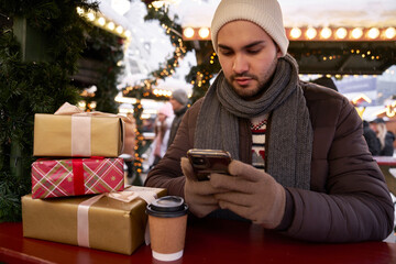 Man browsing phone on Christmas Market