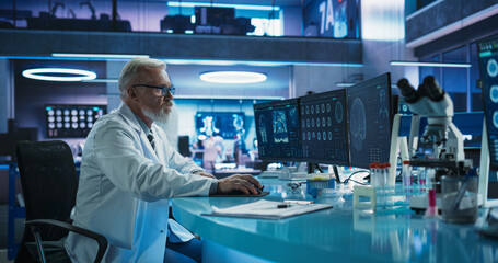 Senior Male Neuroscientist Using Desktop Computer To Analyze MRI Scans Of Brain In Medical Research...