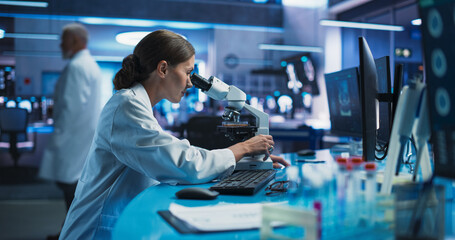 Medical Research And Development Center: Caucasian Female Scientist Using Microscope To Analyze...
