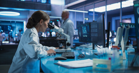 Medicine Development Laboratory: Caucasian Female Scientist Using Microscope, Analyzes Petri Dish...