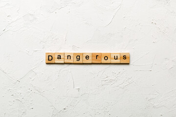 dangerous word written on wood block. dangerous text on cement table for your desing, concept