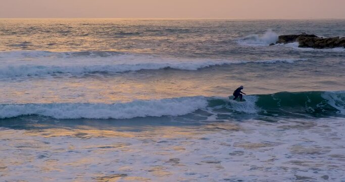 Black male surfer in a bucket hat learning to surf on a small chill wave. Cinematic movie shot, beautiful sunset golden hour clear sky, ocean sea water, colourful refractions. Man slow motion surfing
