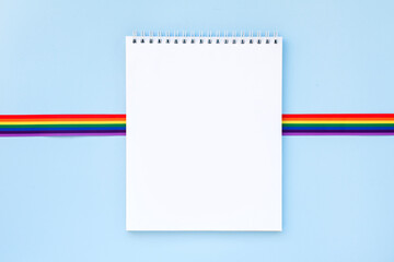 Blank mock up notebook on rainbow LGBTQ flag background. June proud pride month parade, gay marriage, coming out day concept, human rights, tolerance concept. Flat lay, top view place for text or logo