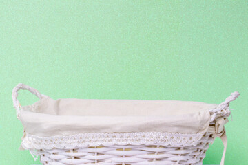 Empty wicker basket over light green glittering background. For your food and product display...