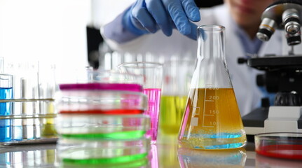 Chemistry industry lubricant oil test concept. Female chemist in blue protective gloves hand hold test tube with yellow liquid. Make analysing sample petroleum gasoline fuel in chemical laboratory.