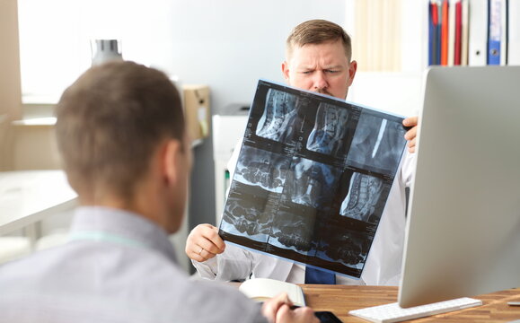 GP examining CT scan detecting problem at office workplace consulting visitor portrait