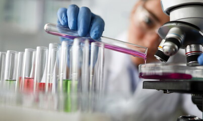 Female chemist holds test tube of glass in hand closeup overflows liquid solution potassium...