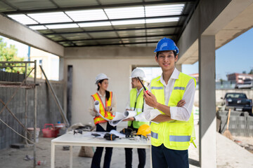 electrical engineer stand with walkie-talkie in construction building and engineer colleagues are working in the background - obrazy, fototapety, plakaty